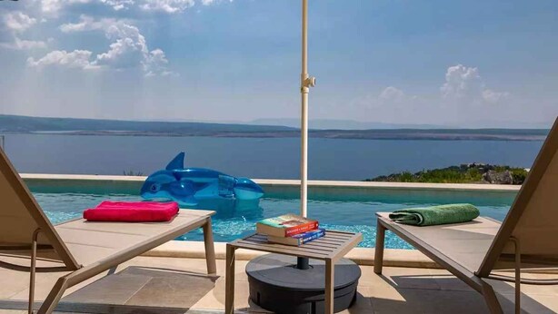 A poolside area with lounge chairs, a table, and an umbrella. - Holiday home with swimming pool fully equipped (Dramalj)