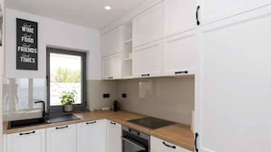 A modern kitchen with white cabinets, a black countertop, and a built-in oven. - Holiday home with swimming pool fully equipped (Dramalj)