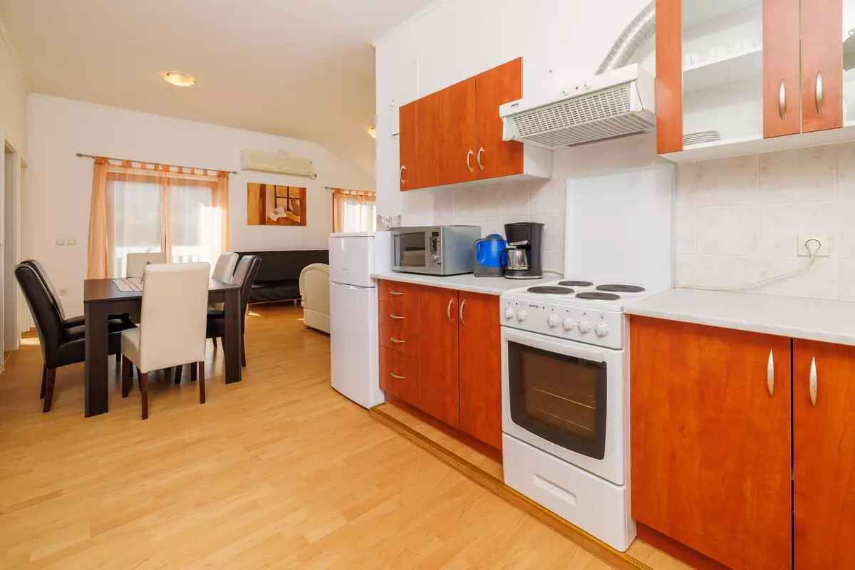 A compact kitchen with wooden cabinets, a microwave, a coffee maker, and a stove.