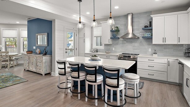 A modern kitchen with a central island, pendant lighting, and a view to the outside.
