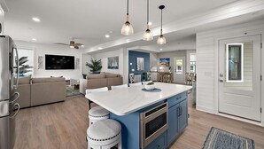A modern kitchen with a central island, blue cabinets, and pendant lighting.