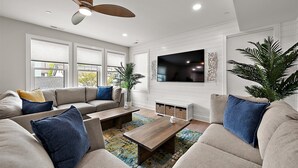 A modern living room with a sofa set, a coffee table, and a TV mounted on the wall.