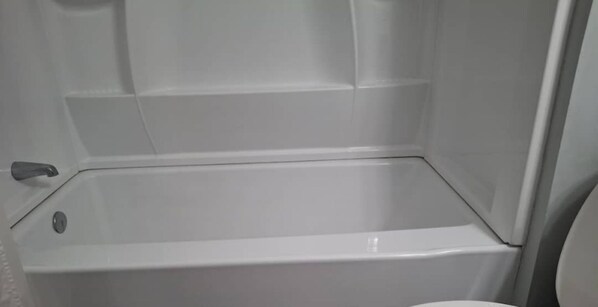 A bathroom with a bathtub, a toilet, and a shower area.