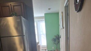 Une cuisine dotée d’un réfrigérateur en acier inoxydable, d’un mur peint en vert et d’une porte donnant sur une autre pièce.