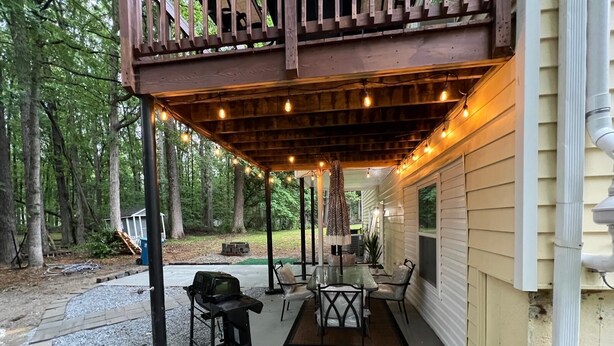 A covered patio with outdoor furniture, a grill, and string lights.