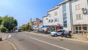 En gatubild med en vit byggnad, en parkerad bil och en motorcykel.