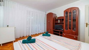 A hotel room with a bed, a TV, a wooden wardrobe, and a white radiator. - Holiday apartment on the promenade (Crikvenica)