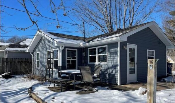 A single-story house with a covered patio, a table, and chairs.