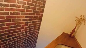 Una escalera con barandilla de madera y pared de ladrillo.