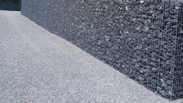 Un tanque de agua y un muro de piedra con un camino de grava.