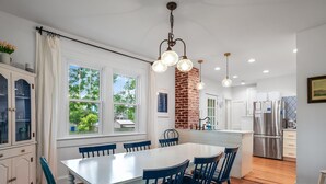 Una cocina moderna con pared de ladrillo decorativa, muebles de cocina blancos y electrodomésticos de acero inoxidable.