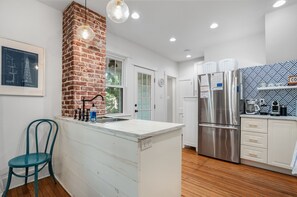 A modern kitchen with a brick column, stainless steel appliances, and a white island.