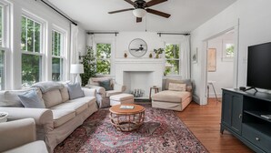 Una sala de estar amplia con chimenea, ventilador de techo y televisor.
