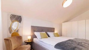 Un dormitorio con cama, una silla, una mesita de noche y un armario.