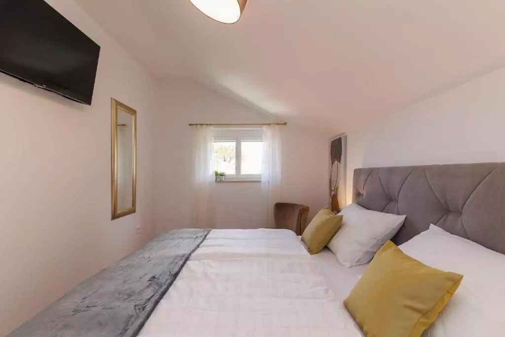 Un dormitorio con cama, televisión, ventana y espejo.