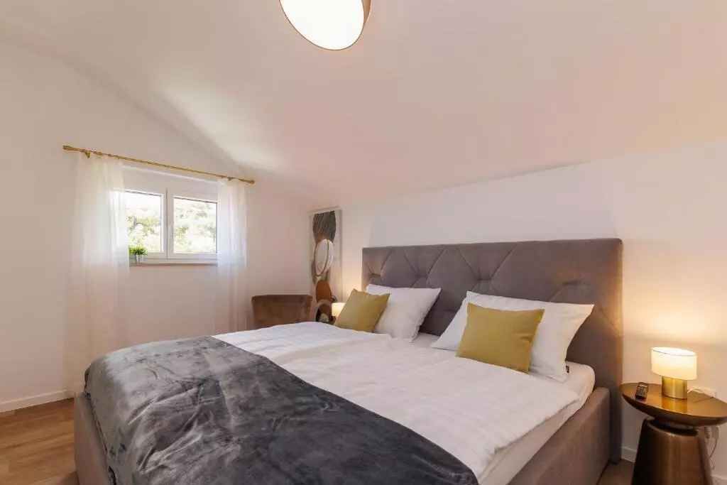 Een slaapkamer met een groot bed, een nachtkastje met lamp, een raam met gordijnen en een spiegel aan de muur.