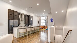 Uma cozinha moderna com armários de madeira, uma geladeira de aço inoxidável e um espaço de bar com banquetas.