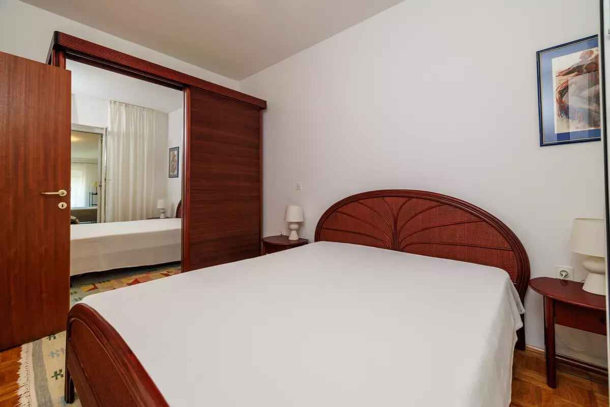 A bedroom with a wooden bed, a nightstand, a bedside table, and a wardrobe.