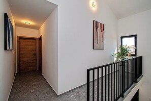 Ein Flur mit einer Holztür, einem gerahmten Kunstwerk und einem Fenster mit Blick.