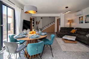 Uma sala de estar moderna com área de jantar, apresentando uma escada, um sofá e uma mesa posta para refeição.