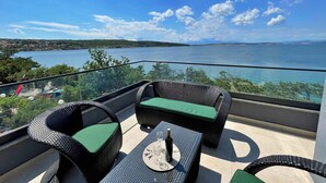En balkon med fletmøbler og udsigt over et sø.