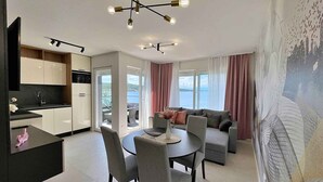 En moderne stue med spiseområde, et køkken og en balkon med havudsigt.