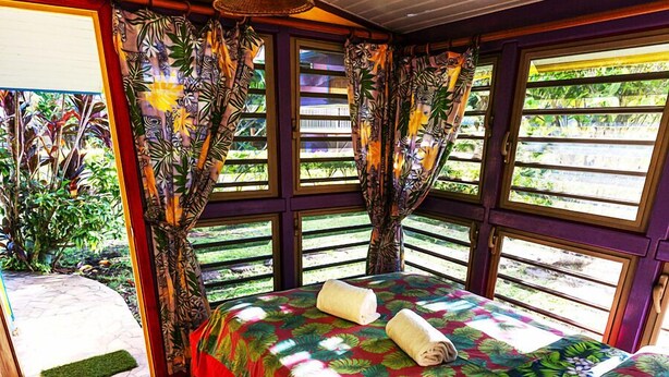 Un dormitorio con cama, cortinas y vista a la vegetación.