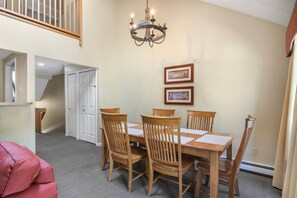 A dining area with a table and chairs, a chandelier, framed pictures on the wall, and a staircase leading to an upper level. - Traverse City/Horse show/Hiking (Williamsburg)
