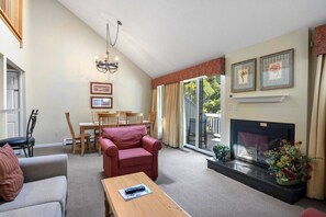 A living room with a fireplace, a dining area, and a large window. - Traverse City/Horse show/Hiking (Williamsburg)