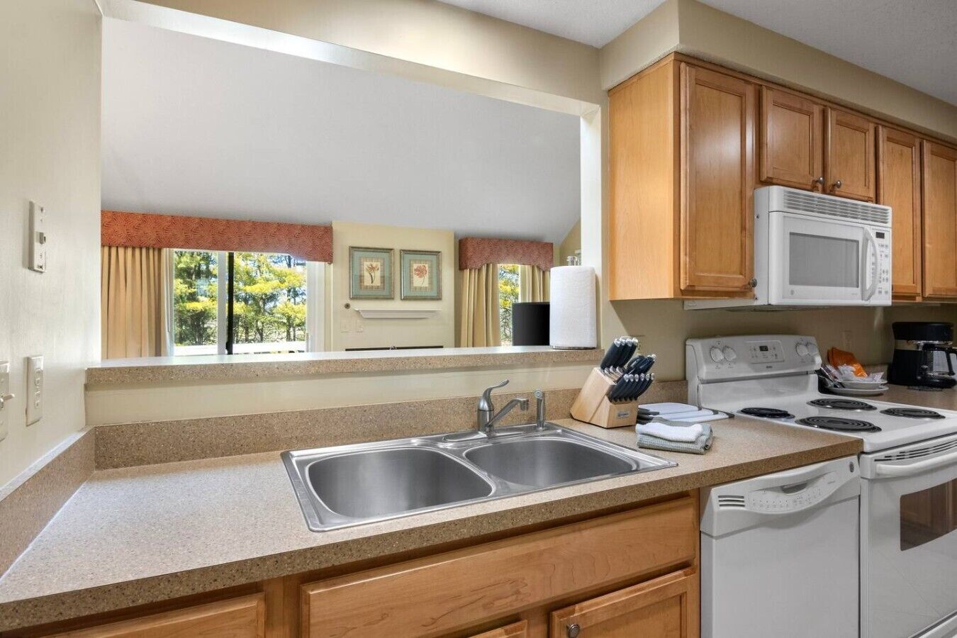 A kitchen with a double sink, a stove, and wooden cabinets.