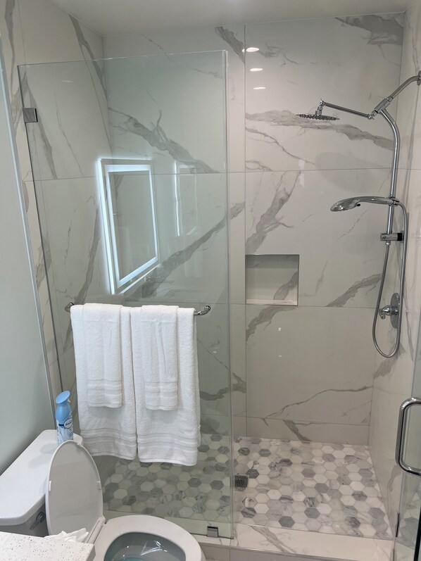 Un baño moderno con ducha de vidrio, inodoro y lavamanos.