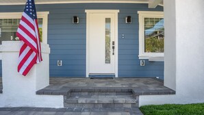 A front porch with a white door, steps leading up to it, and an American flag.