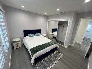 Un dormitorio moderno con una cama grande, mesitas de noche, un armario y un vestidor.