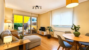 A modern living room with a sofa, a dining table, a TV, and a potted plant.
