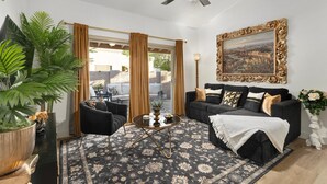 A living room with a black sofa, a coffee table, and a large potted plant. - Stylish Chandler Stay - 2 King Beds, 2 Baths! (Chandler)