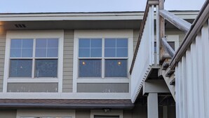 Une maison à deux étages avec une porte d’entrée verte, un porche abrité et un escalier menant à l’étage supérieur.
