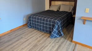Une chambre à coucher avec un lit, une tête de lit en bois et un petit banc en bois.
