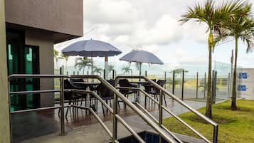 Zona de piscina con escalones de acceso, mobiliario exterior y sombrillas.