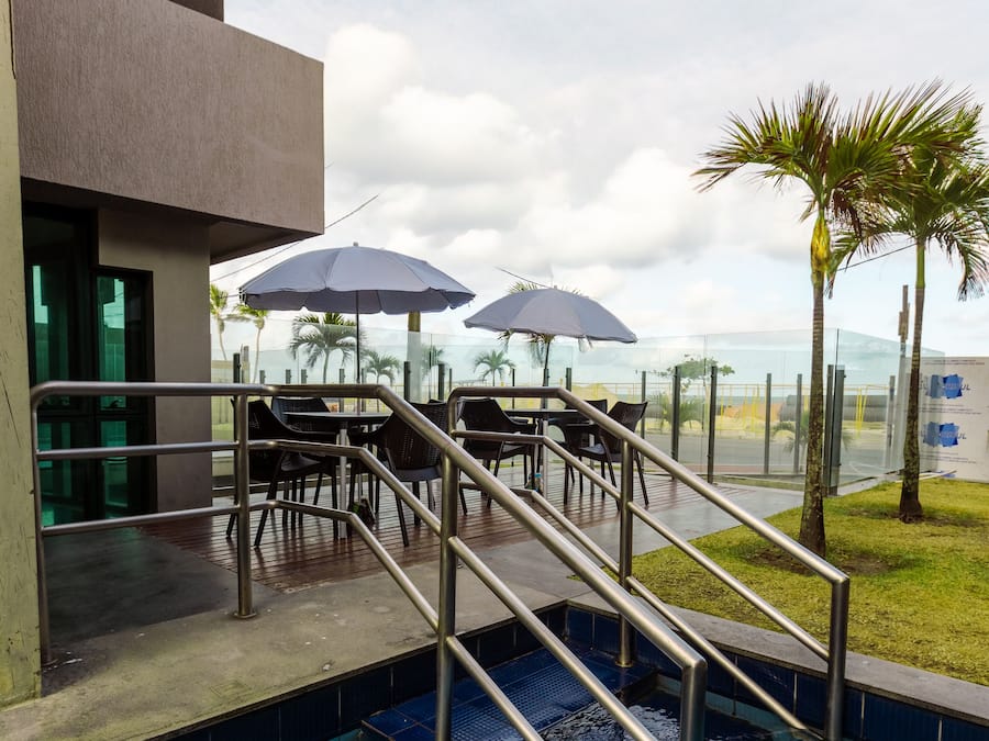 A swimming pool area with steps leading into the water, outdoor seating, and umbrellas.