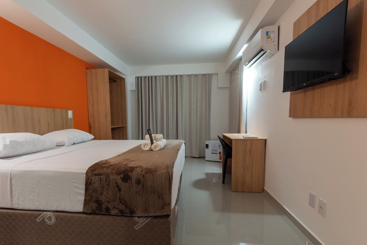 Una camera d'albergo con un letto, una scrivania, una televisione e un condizionatore.