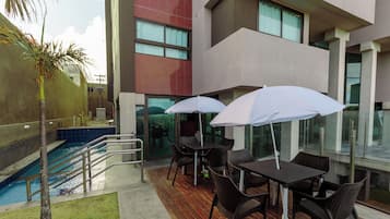 Un área de piscina en la azotea, con piscina, sillas y sombrillas.