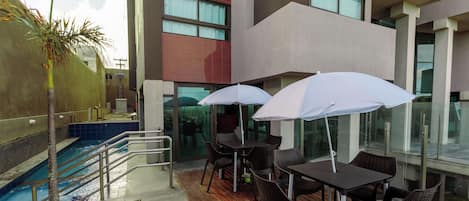 A rooftop pool area with a pool, chairs, and umbrellas.