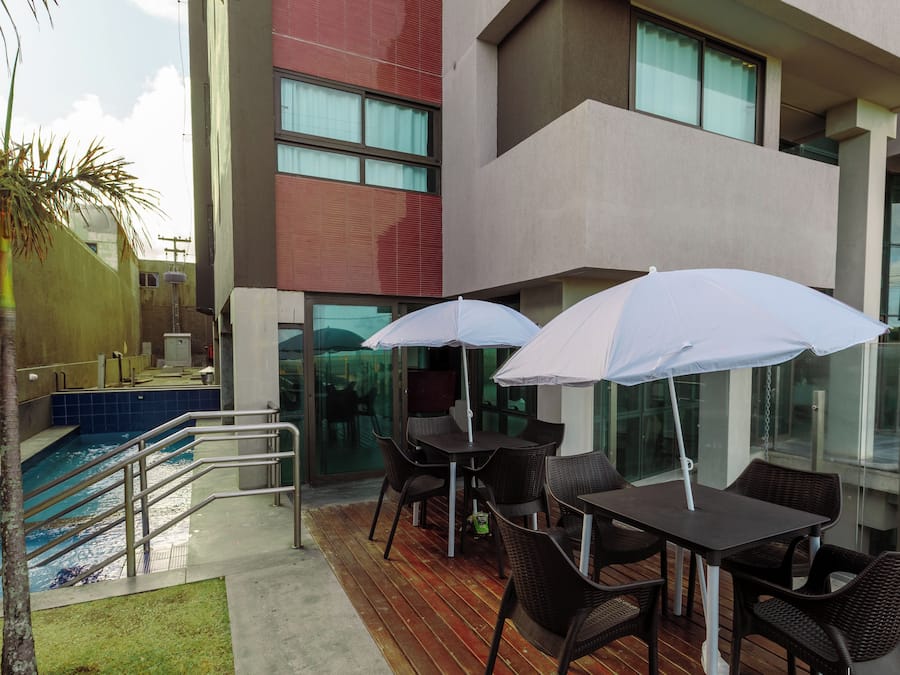 A rooftop pool area with a pool, chairs, and umbrellas.