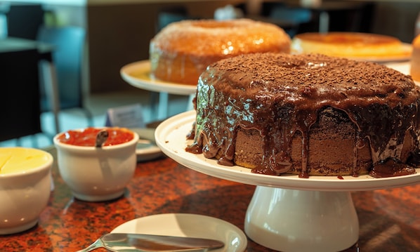 A chocolate cake with chocolate drizzle on a white cake stand. - Rede Andrade Boa Viagem (Jaboatão dos Guararapes)