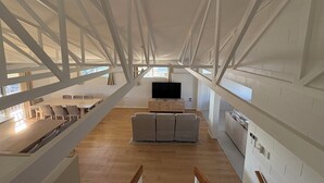Un interior espaiós amb sostres alts, una zona de seients central i una cuina visible al fons.