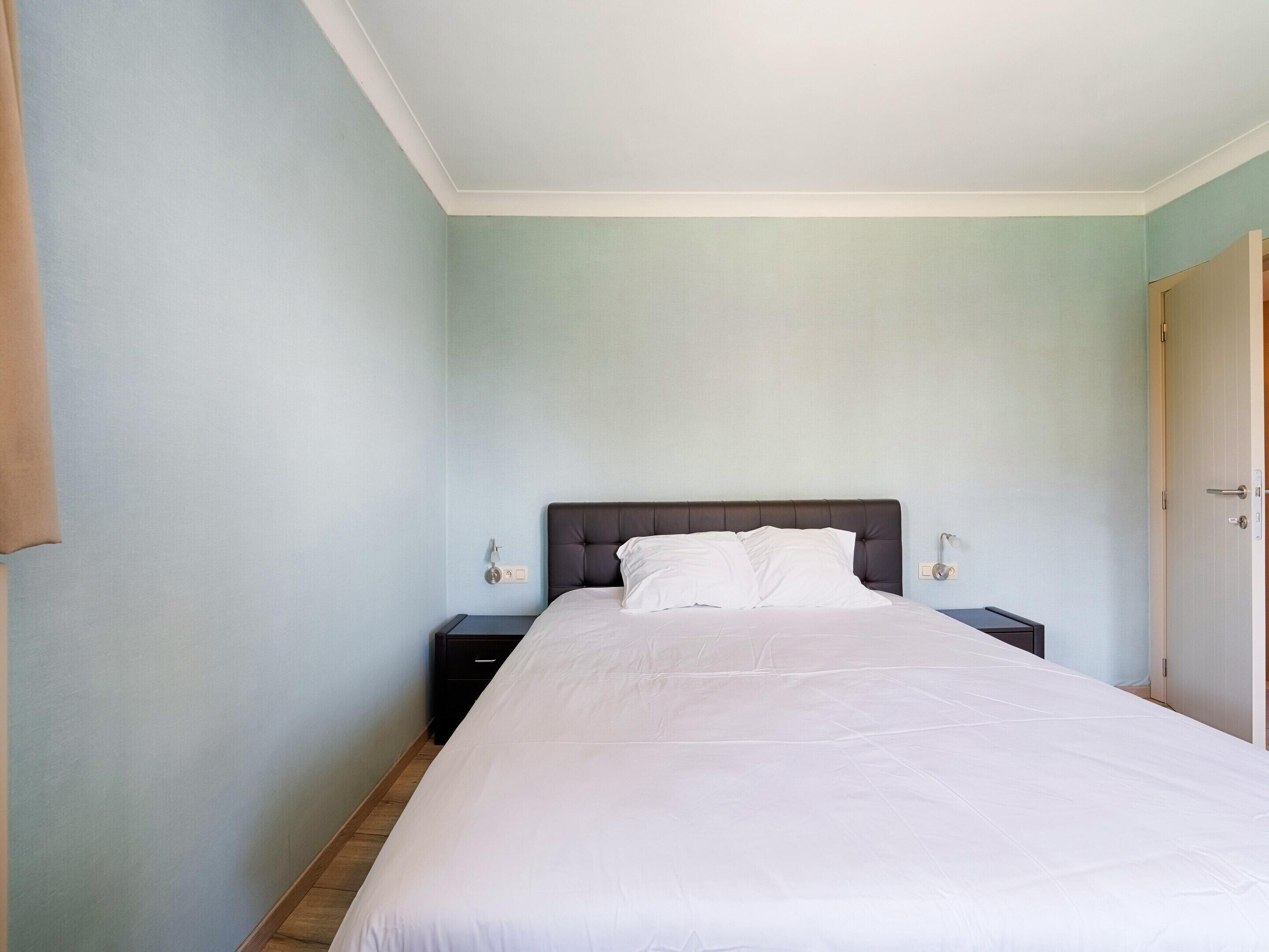 Ein Schlafzimmer mit einem großen Bett, zwei Nachttischen und einer Tür.