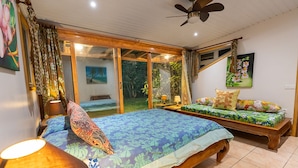 Un dormitorio con dos camas, ventilador de techo y vista al exterior.