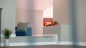 A modern living room with a blue sofa, a white bench, and a small table with boxes.