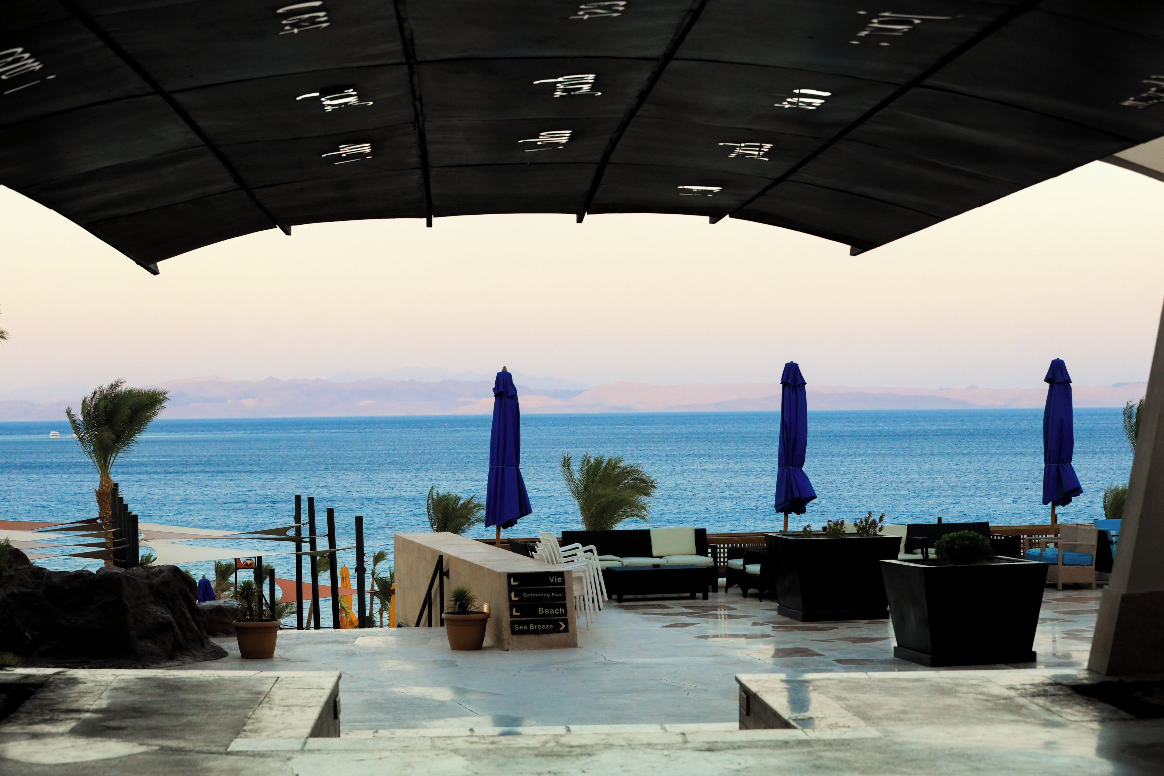 Une terrasse avec des places assises extérieures, une vue sur la mer et des panneaux de signalisation.