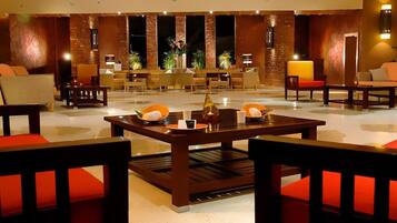 A lobby with a reception desk, seating area, and a decorative centerpiece on the table.